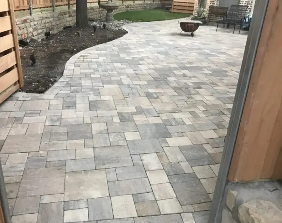 Paver patio with a curved border and fire pit behind a cedar fence