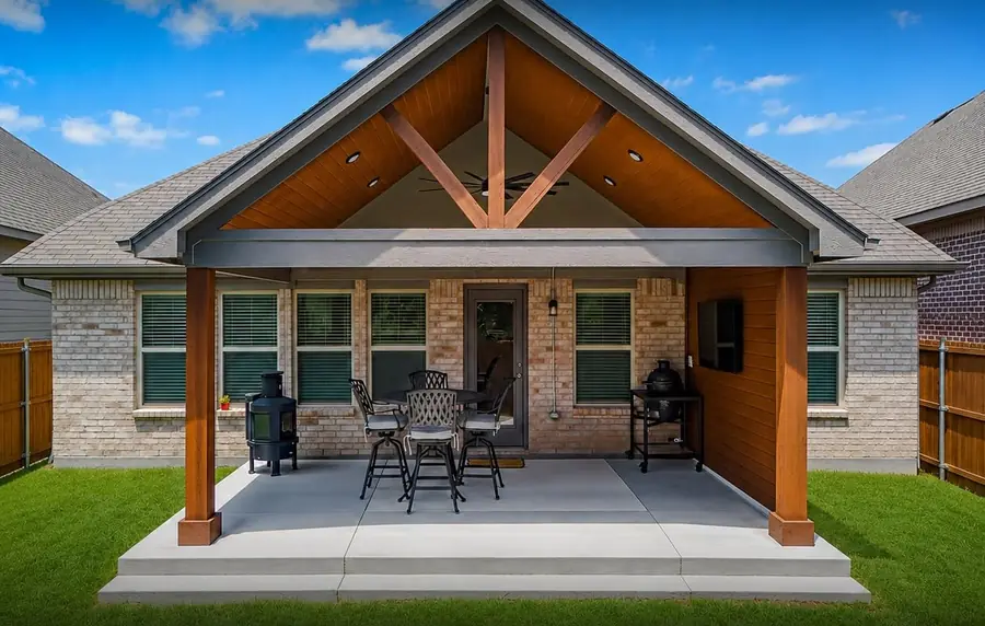 Gabled cedar patio cover with stained tongue-and-groove ceiling on a brick home