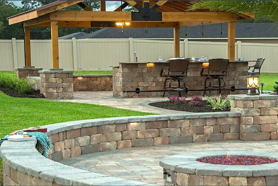 Curved stone seating wall, fire pit and a bar under a cedar pavilion