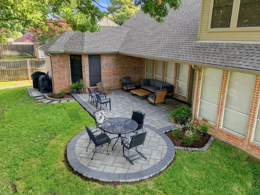 Aerial view of a grey paver patio with a circular dining pad and a charcoal border