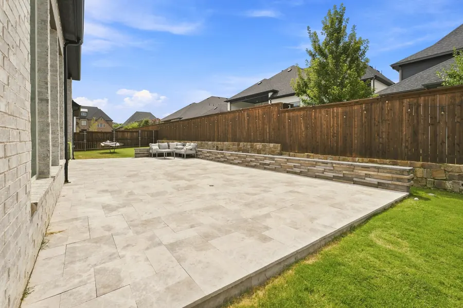Travertine patio beside a stacked-stone seating wall along a cedar fence